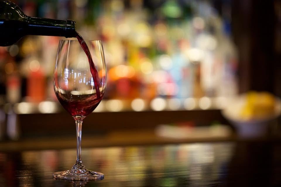 Red wine being poured into a glass at the bar