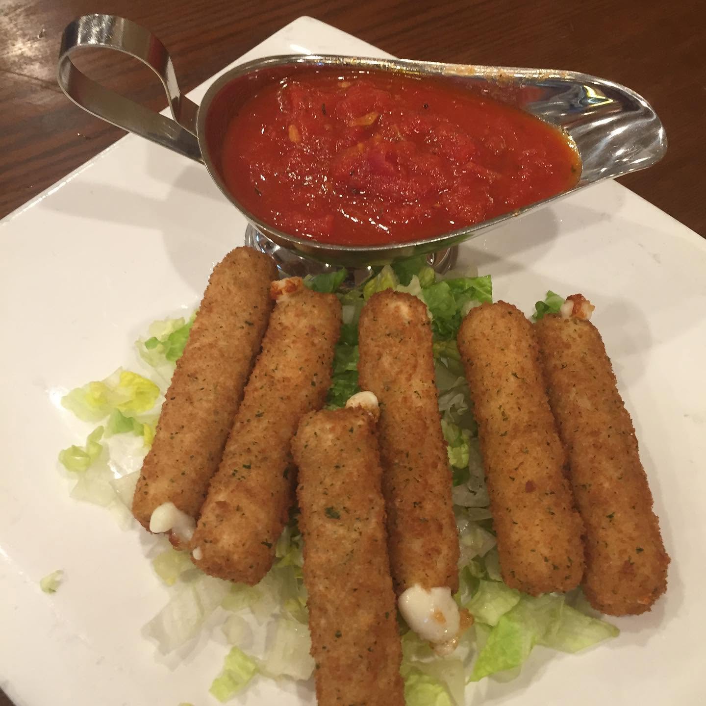 Fried mozzarella sticks on a bed of lettuce