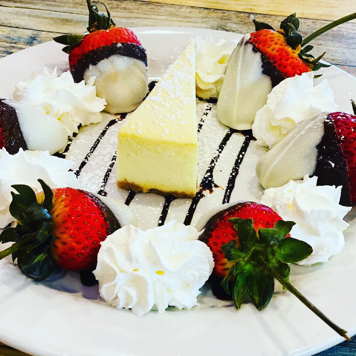 Cheesecake slice with chocolate-covered strawberries and whipped cream