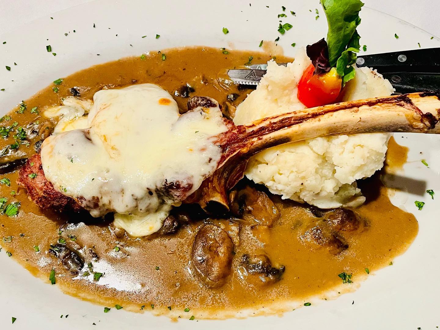 Veal chop topped with melted mozzarella and mushroom gravy