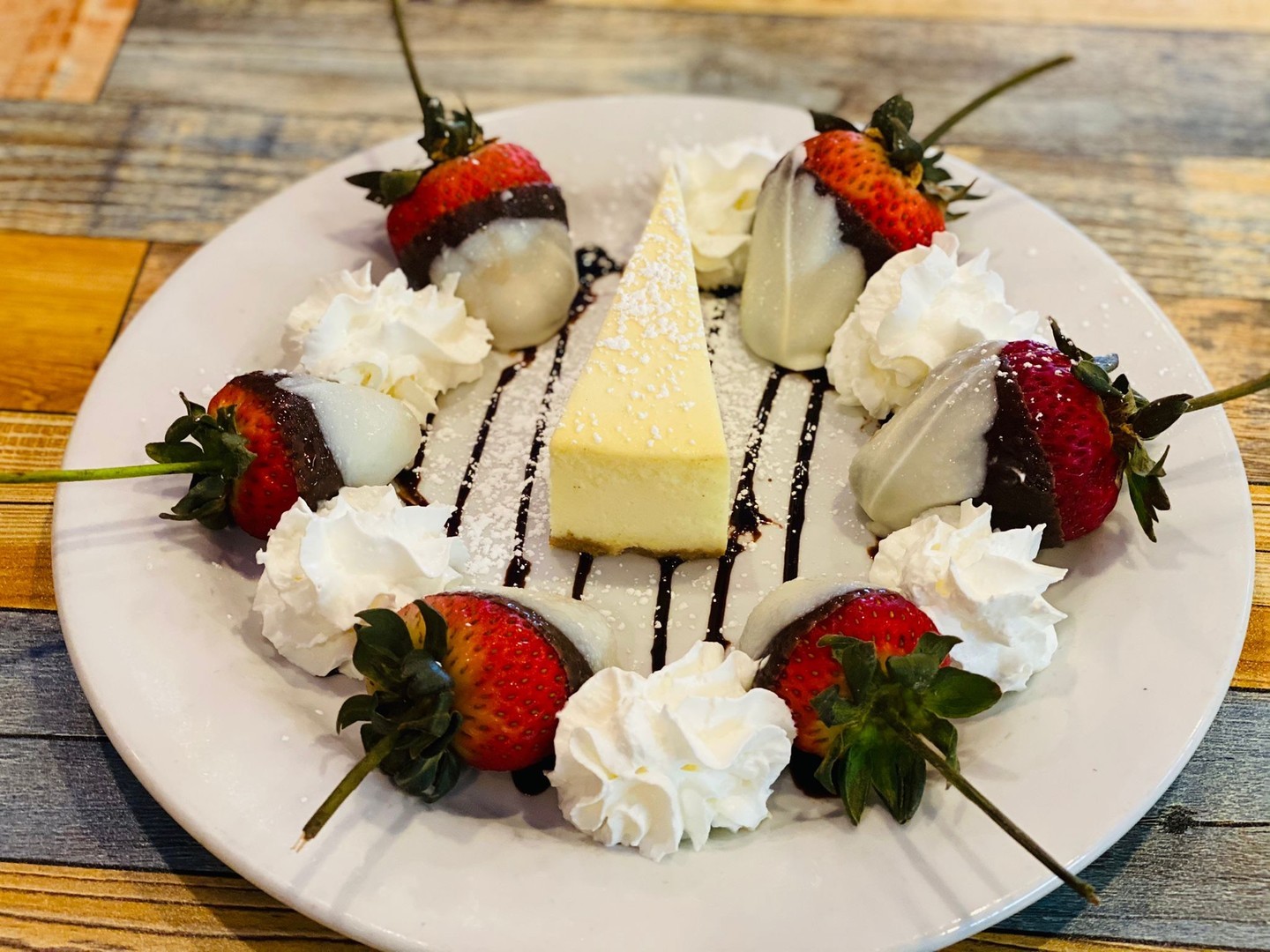 Cheesecake slice with chocolate-dipped strawberries and whipped cream
