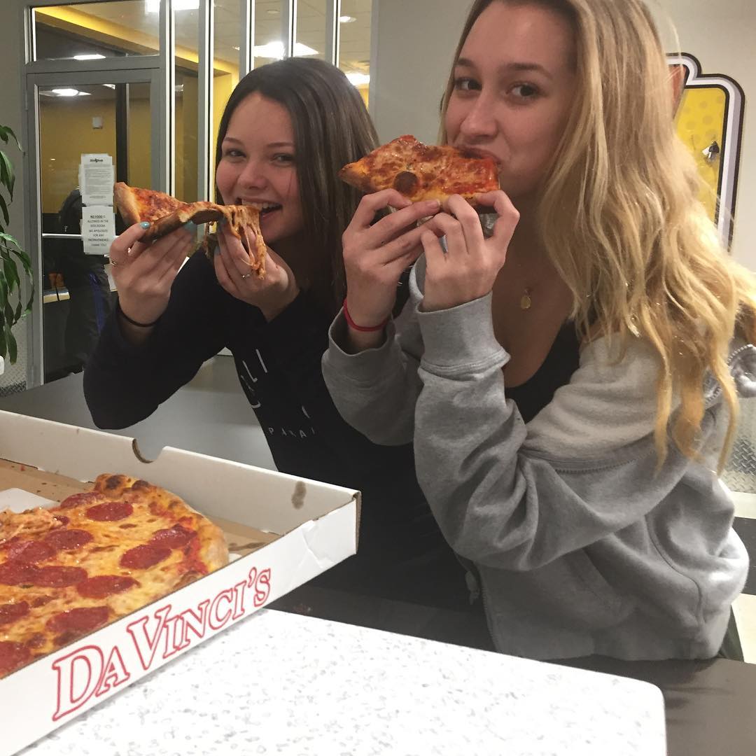 Two women eating pizza slices from a Da Vinci's box