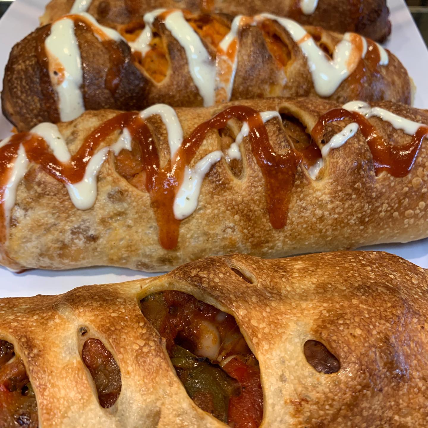 Buffalo chicken stromboli rolls drizzled with ranch and hot sauce