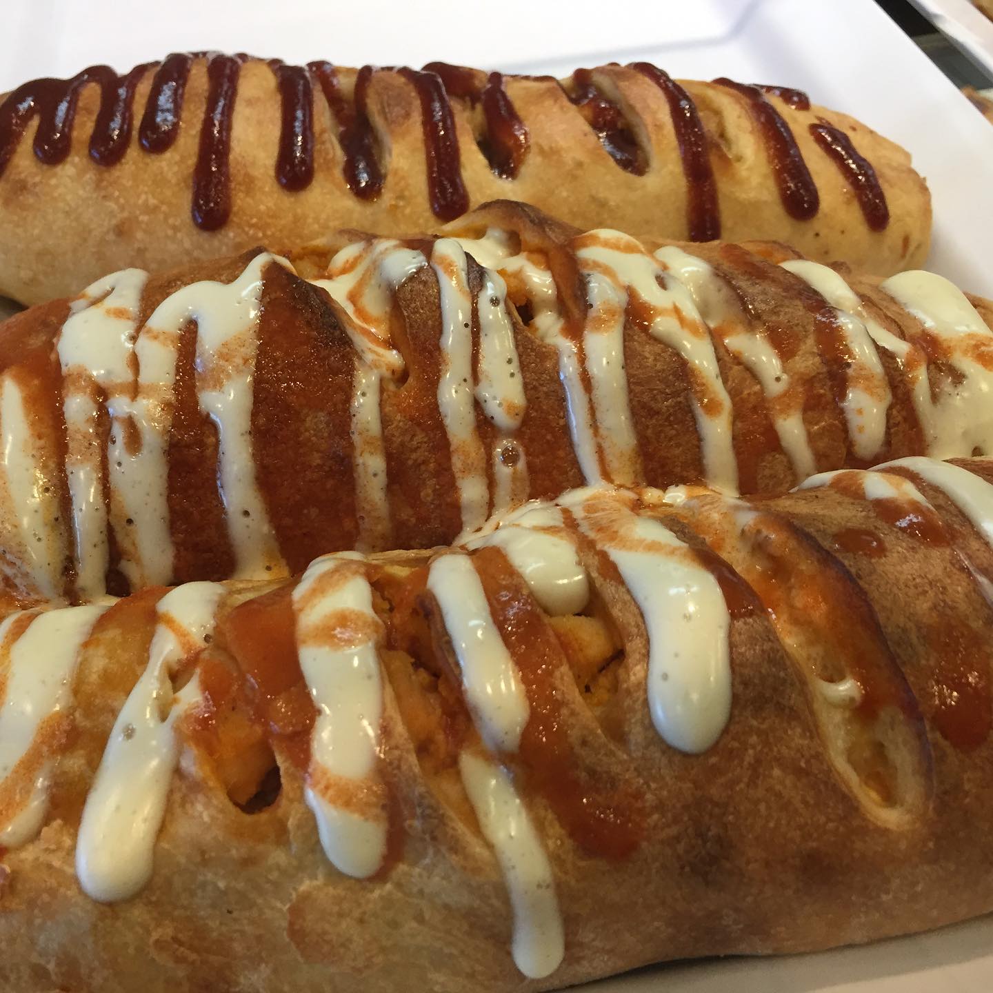 Stuffed stromboli rolls drizzled with marinara and creamy sauce