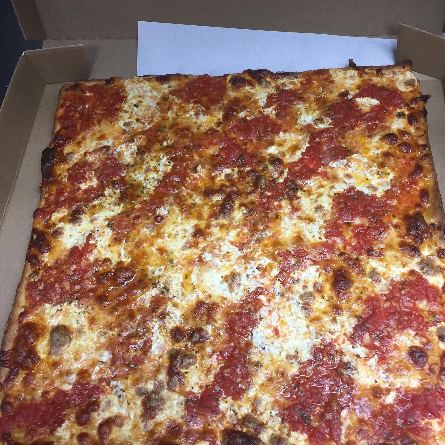 Sicilian square pizza with tomato and mozzarella in a to-go box
