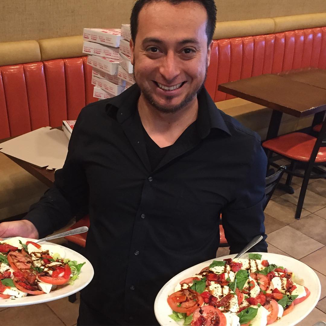 Server holding two caprese salad plates in the dining room